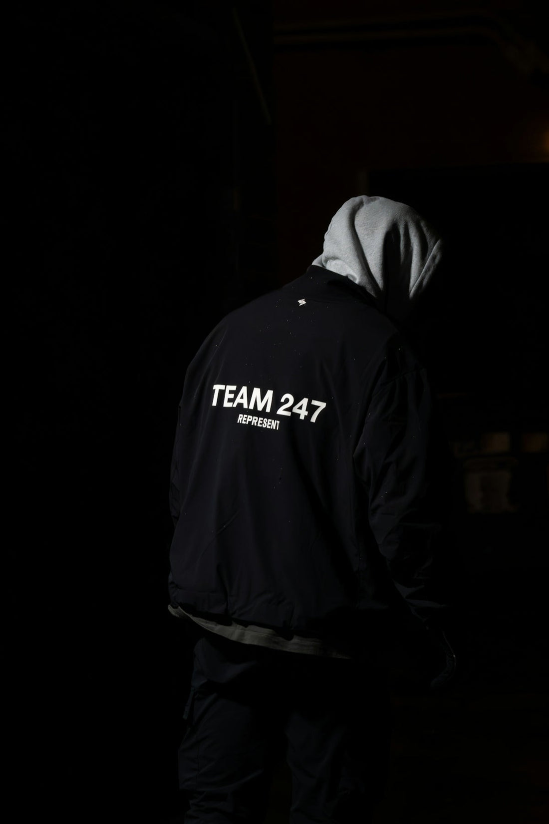 A man in a hoodie standing in the dark